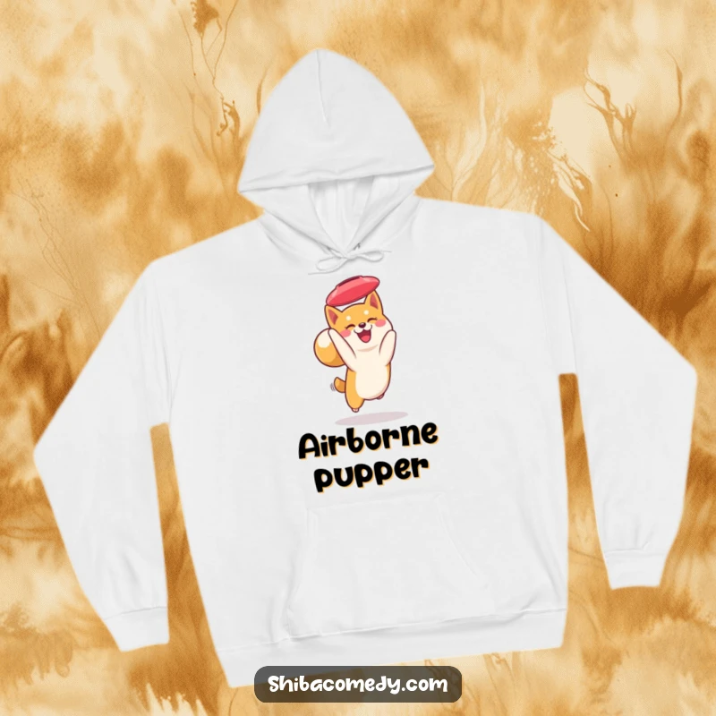 Funny Shiba Inu hoodie: a smiling Shiba Inu with a curled tail catches a frisbee mid-flight, offering cozy comfort and doggy charm.